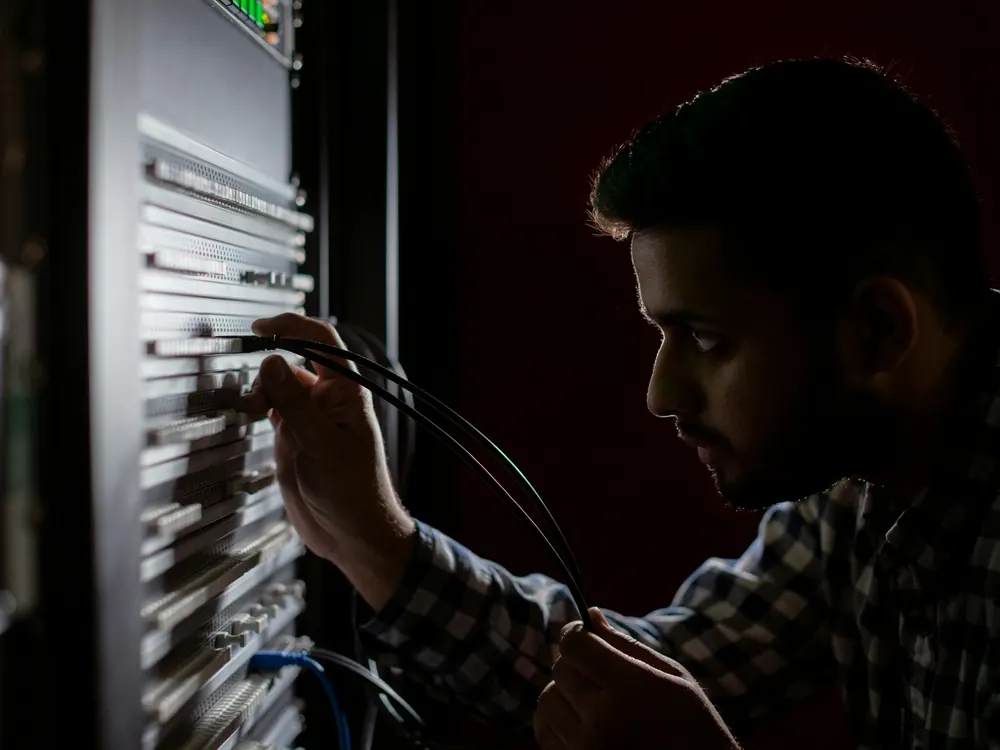 Sunucu kabininde kablo bağlantılarını kontrol eden bir teknisyen